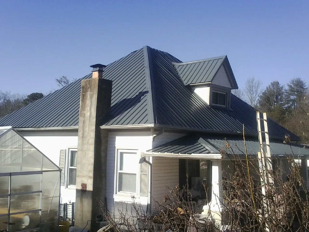 Dark blue standing seam metal roof on a white farmhouse with dormer — Slate & Tile Roof Repair by Roofing Brothers in Fairfield